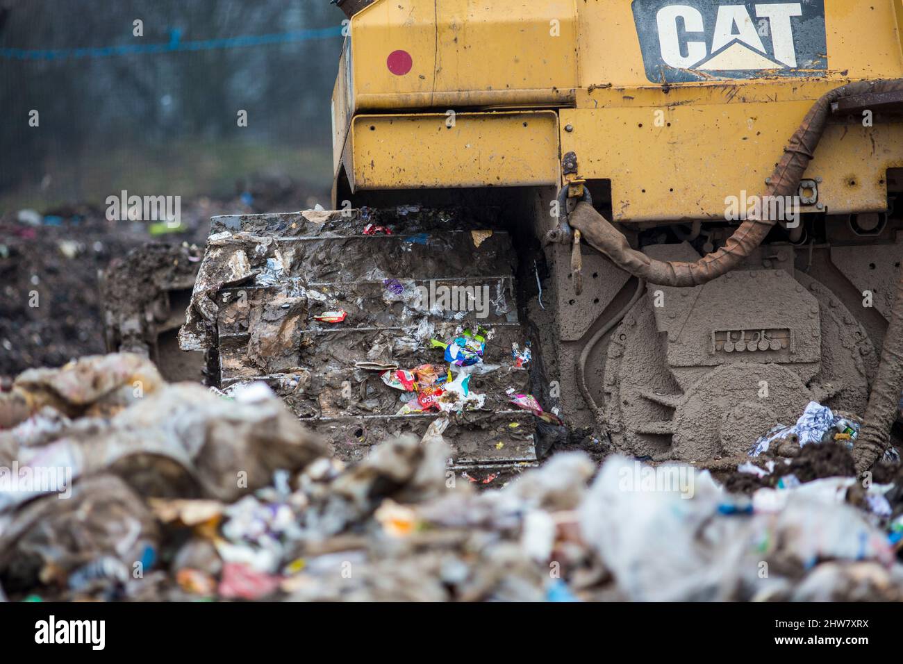 A Caterpillar bulldozer blade and tracks compact household waste on a UK waste disposal site. Stock Photo
