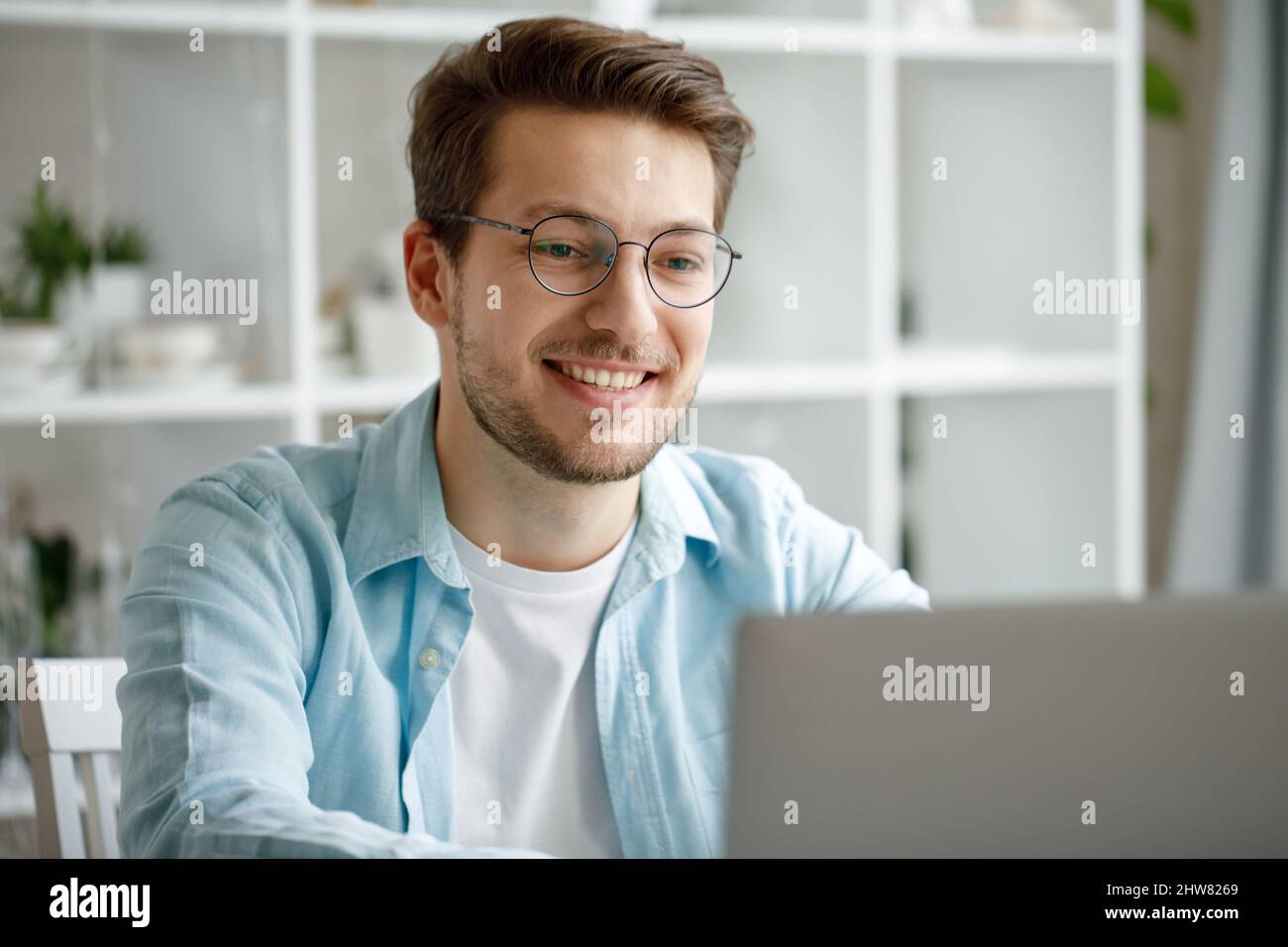 An attractive young man is working on a laptop. Stock Photo