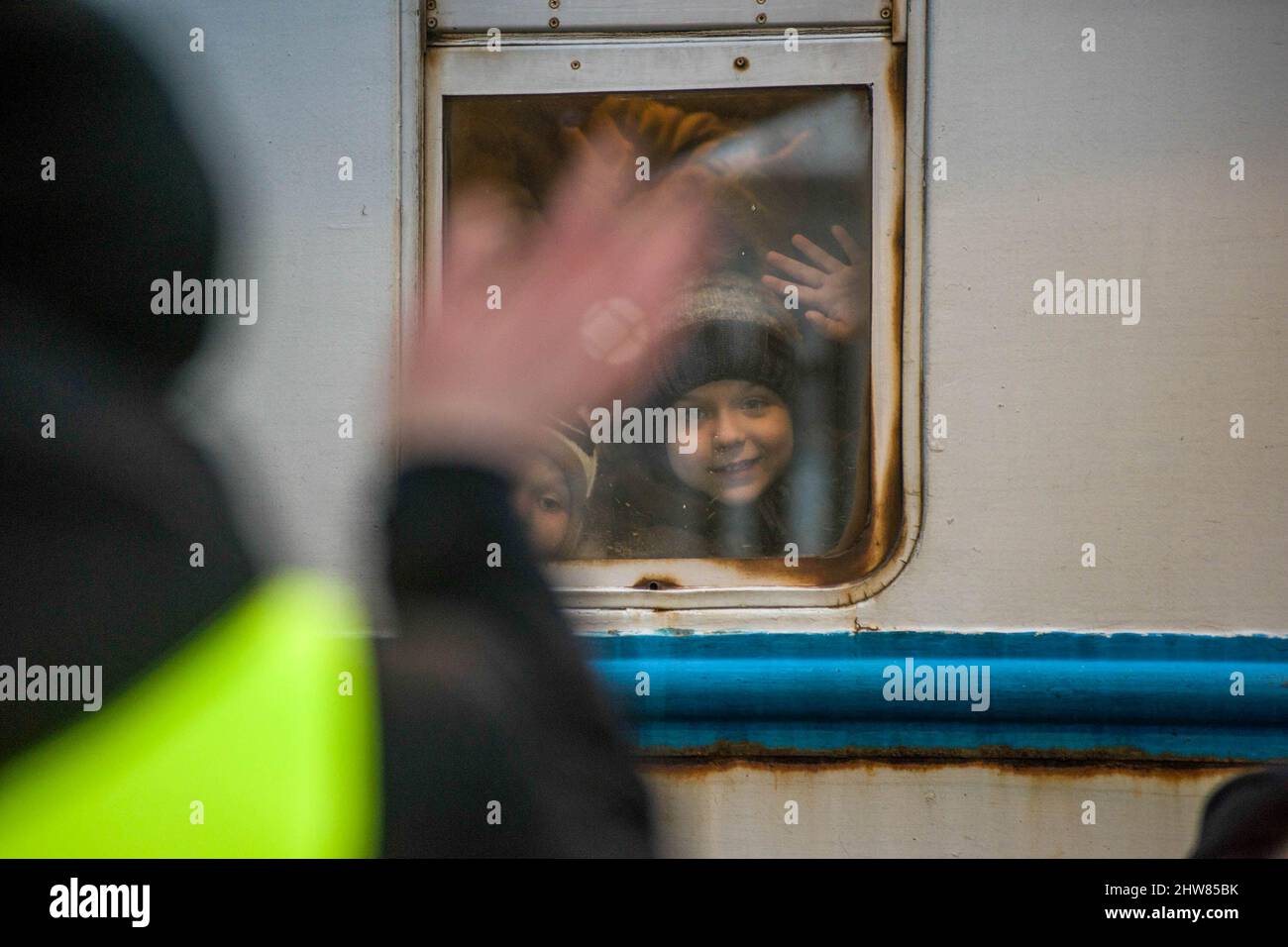 Przemysl, Poland. 03rd Mar, 2022. A boy waves to a volunteer through the window of the train that arrived from Ukraine to Przemysl train station. On the 8th day of the Russian invasion in Ukraine thousands of exhausted refugees fleeing war are arriving to the Polish border town of Przemysl. Credit: SOPA Images Limited/Alamy Live News Stock Photo
