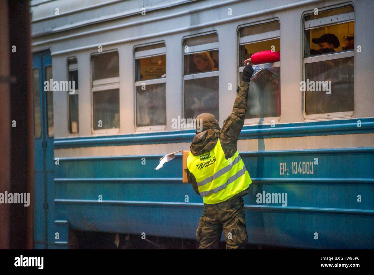 A soldier distributes food through the window of the train that arrived from Ukraine to Przemysl train station. On the 8th day of the Russian invasion in Ukraine thousands of exhausted refugees fleeing war are arriving to the Polish border town of Przemysl. (Photo by Attila Husejnow/SOPA Images/Sipa USA) Credit: Sipa USA/Alamy Live News Stock Photo