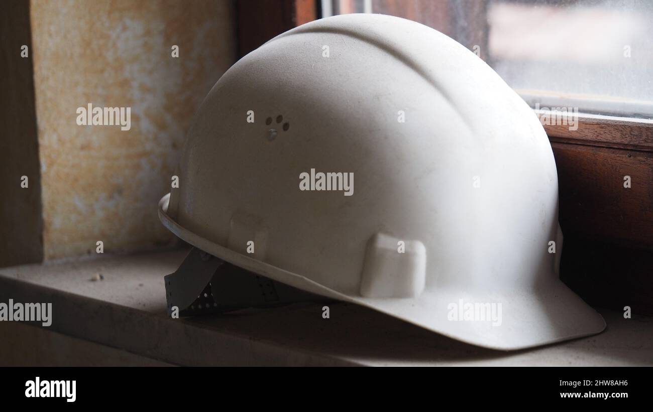 Closeup photo of a white construction helmet on a window sill Stock