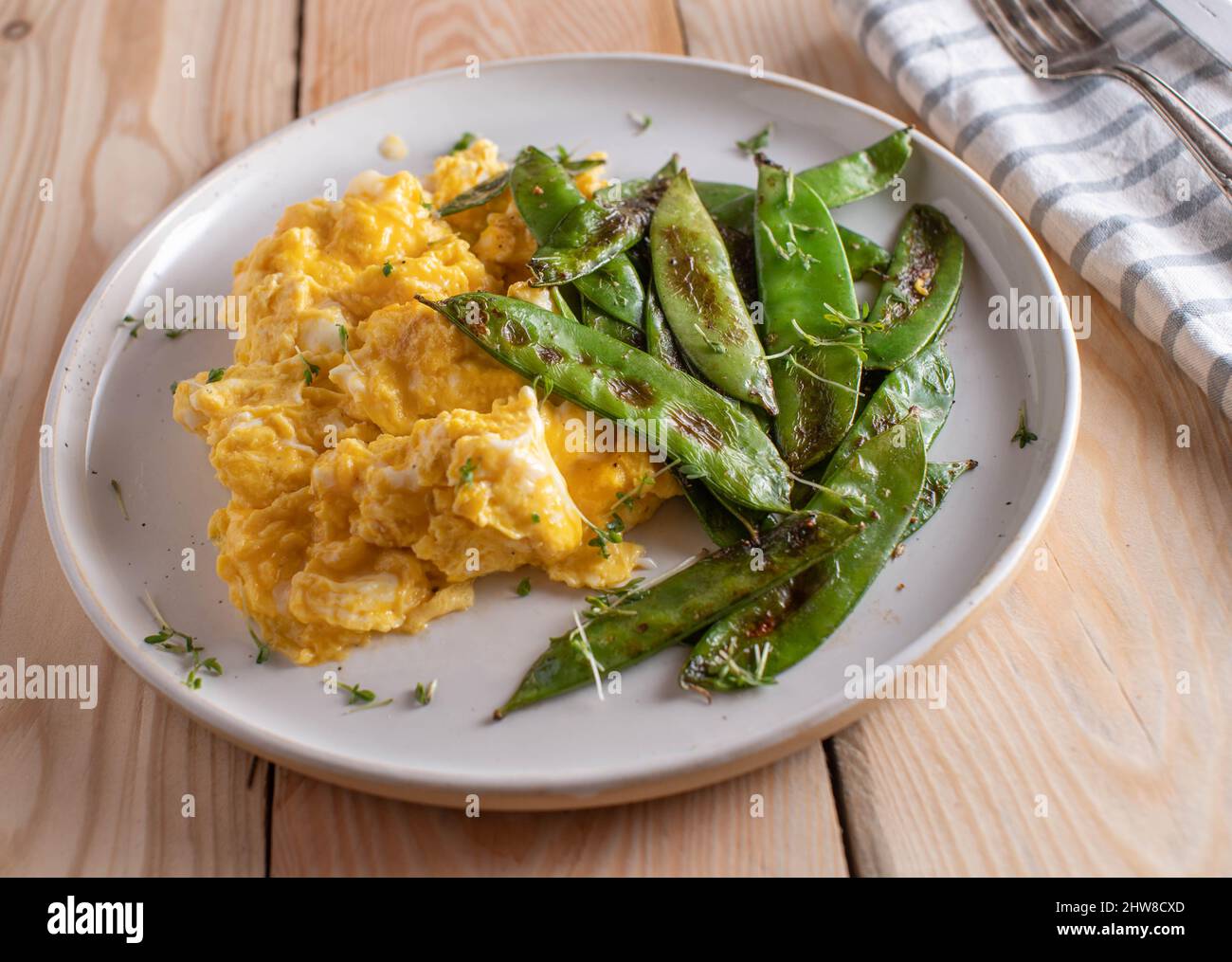 Scrambled eggs with buttered and roasted sugar snap peas. Healthy breakfast for low carb or ketogenic diet Stock Photo