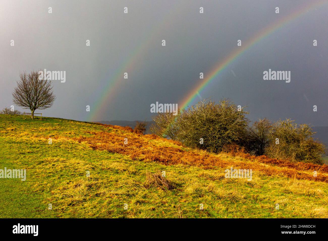 Rainbow and dark sky with rolling countryside near Oaker in the Derbyshire Dales area of the Peak District National Park, Derbyshire, England, UK Stock Photo