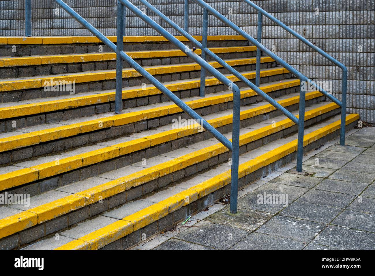 Outdoor concrete steps with yellow safety markings and handrails