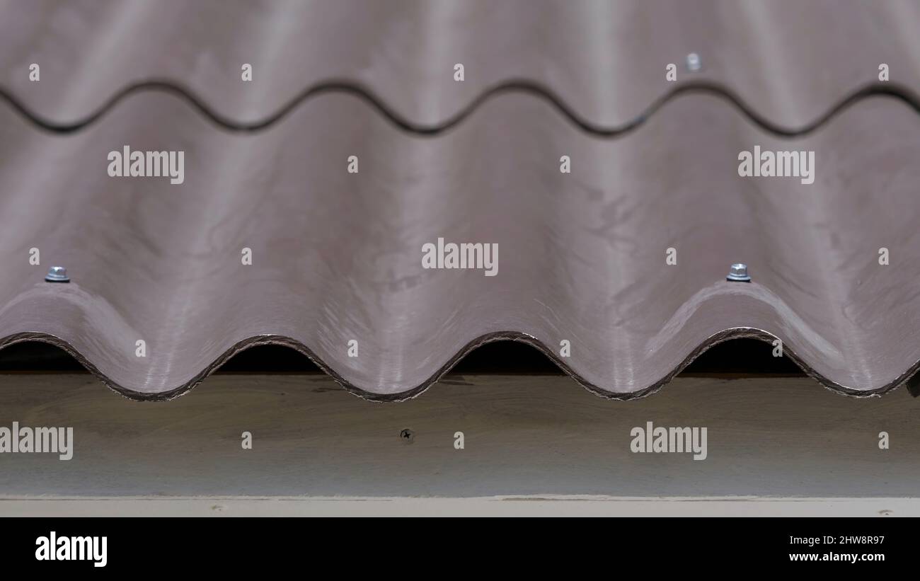 Closeup of roof tiles at home. Curved wavy roof tile of house is made