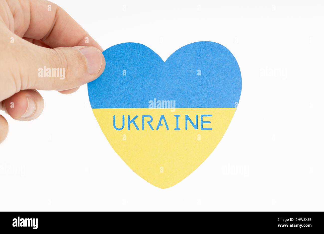Hand holding a Flag of Ukraine on heart shape. White background Stock Photo