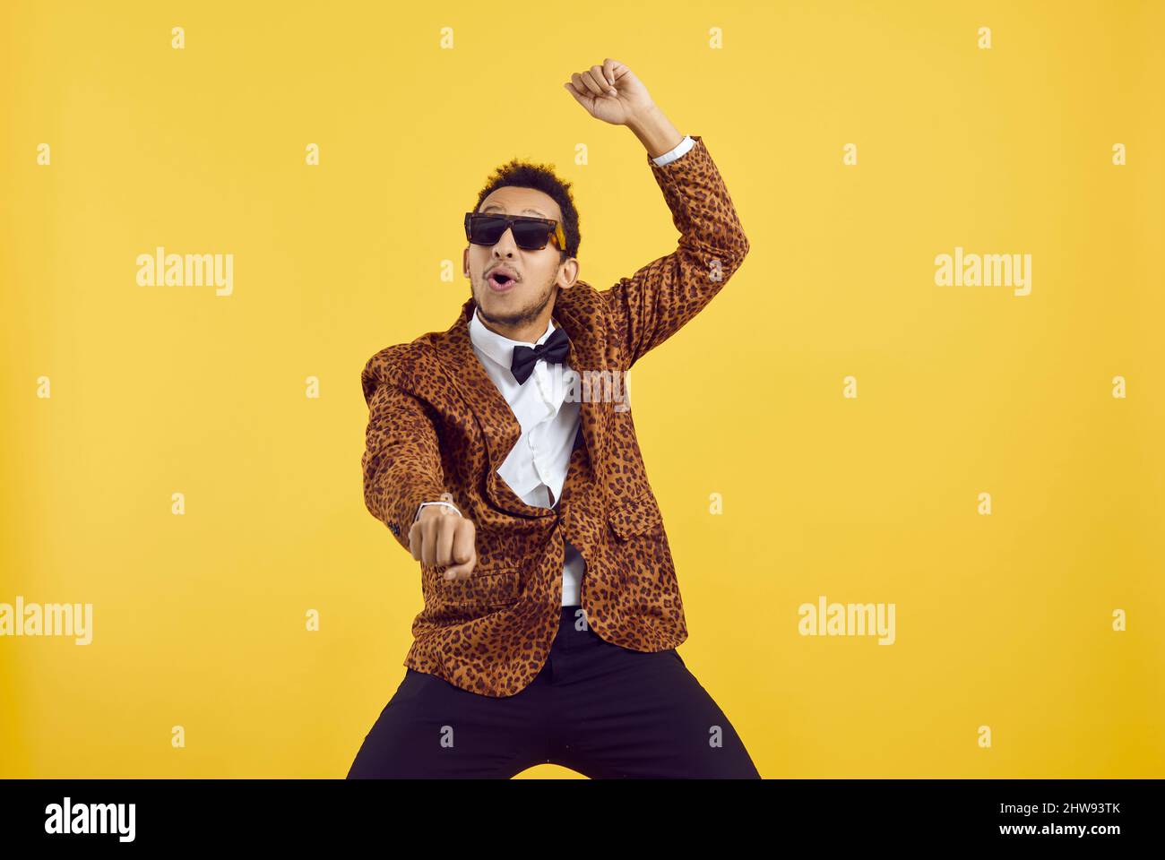 Happy funny black guy in a leopard jacket dancing gangnam style on a yellow background Stock Photo