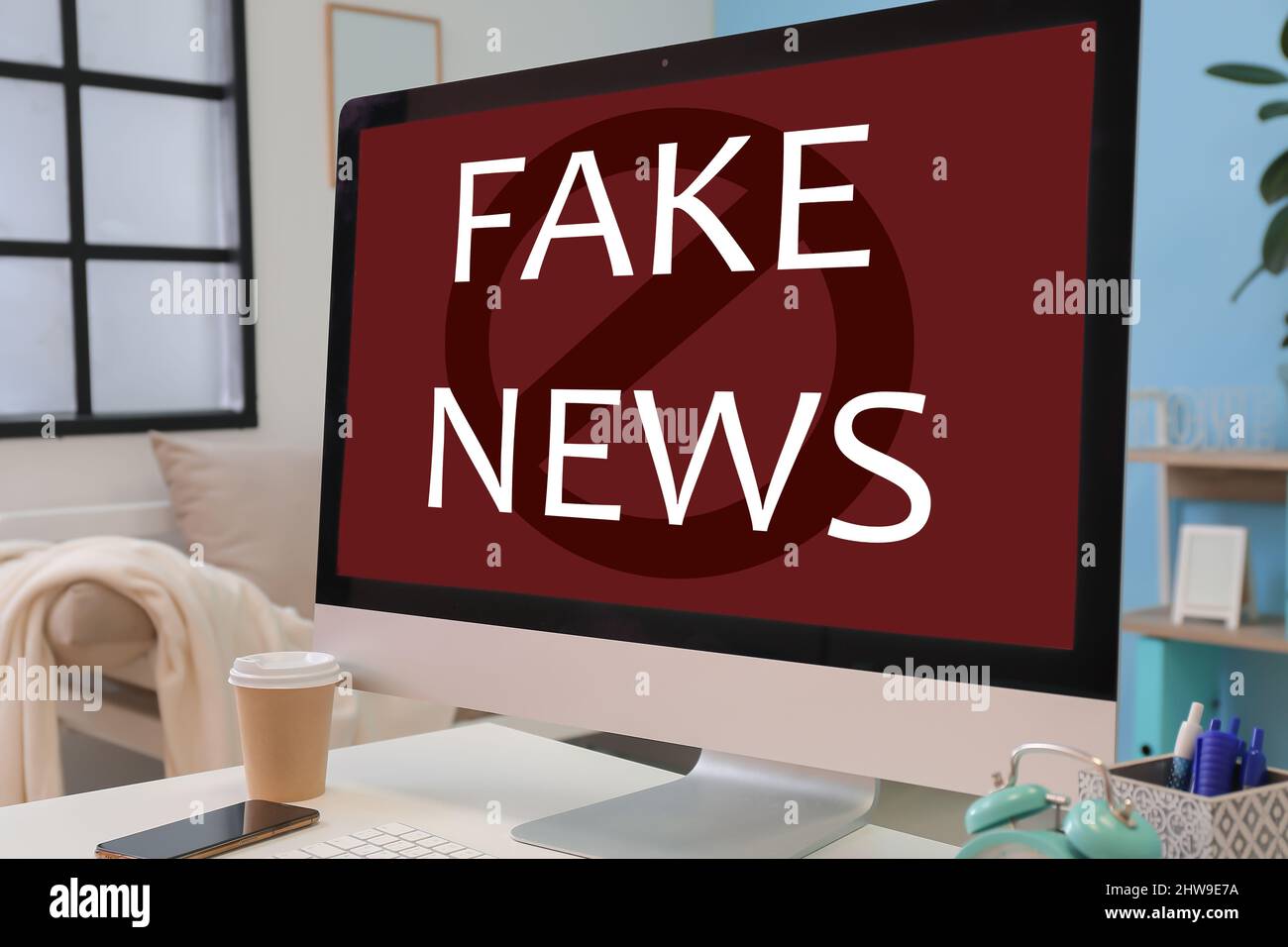 Text FAKE NEWS on screen of computer monitor on table Stock Photo - Alamy