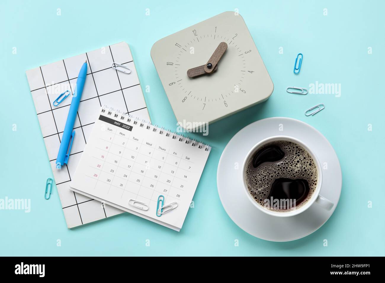 New alarm clock with cup of coffee and stationery on blue background ...