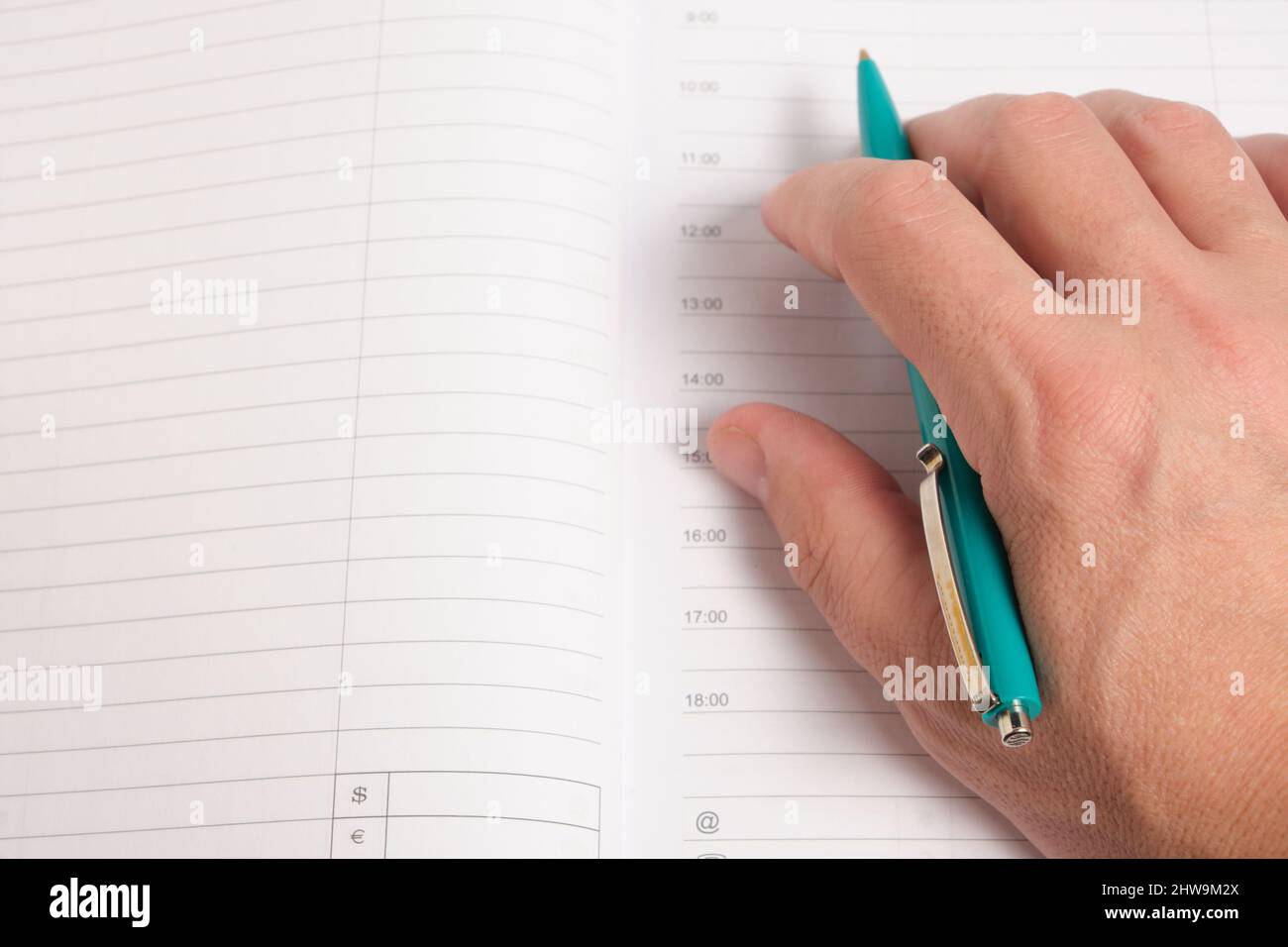 Hand with green ballpoint pen on background notepad sheets Stock Photo