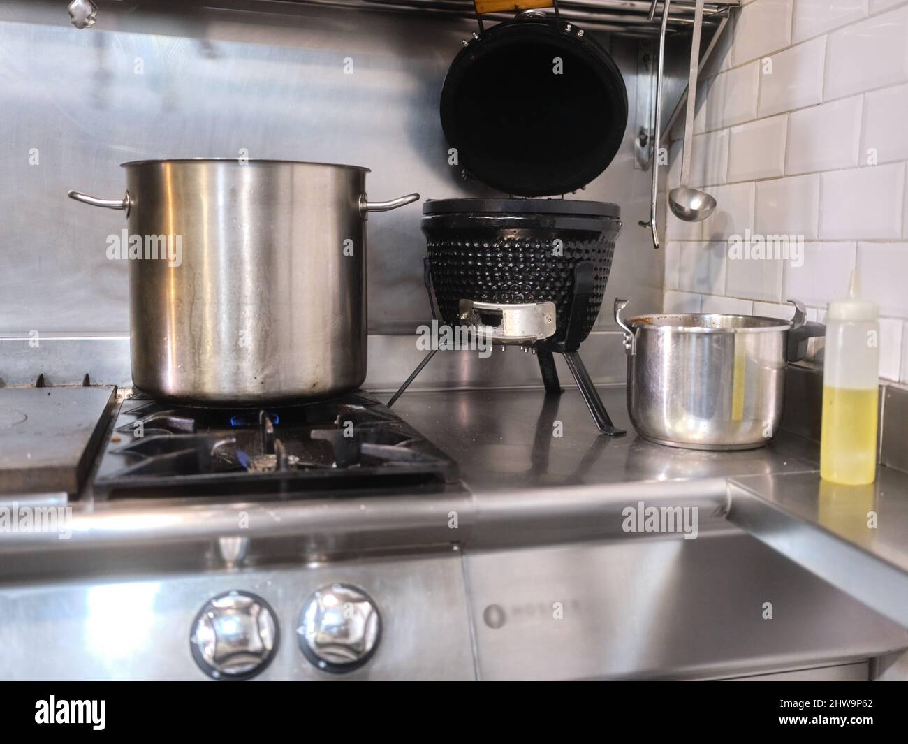 Large pot on the cooker of a restaurant next to oil and an electric fryer Stock Photo