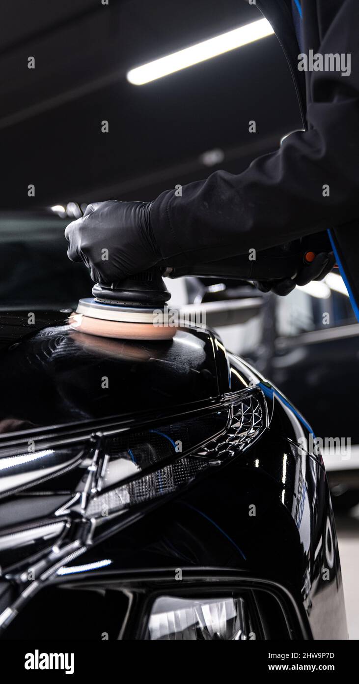 Car detailing studio technician polishing black car paint Stock Photo