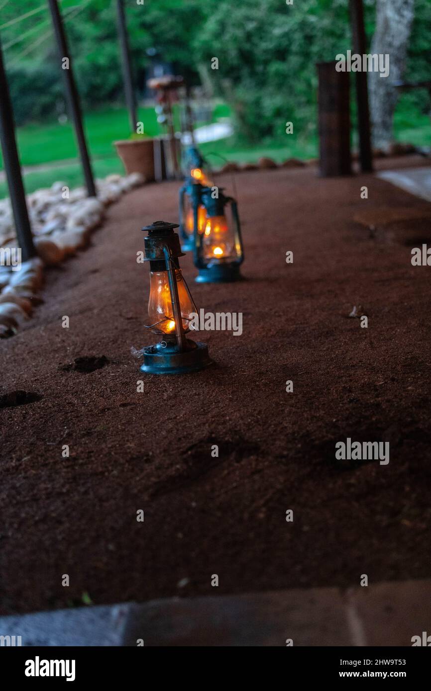 Vertical shot of three kerosene lamps on brown sand outdoors in Maasai