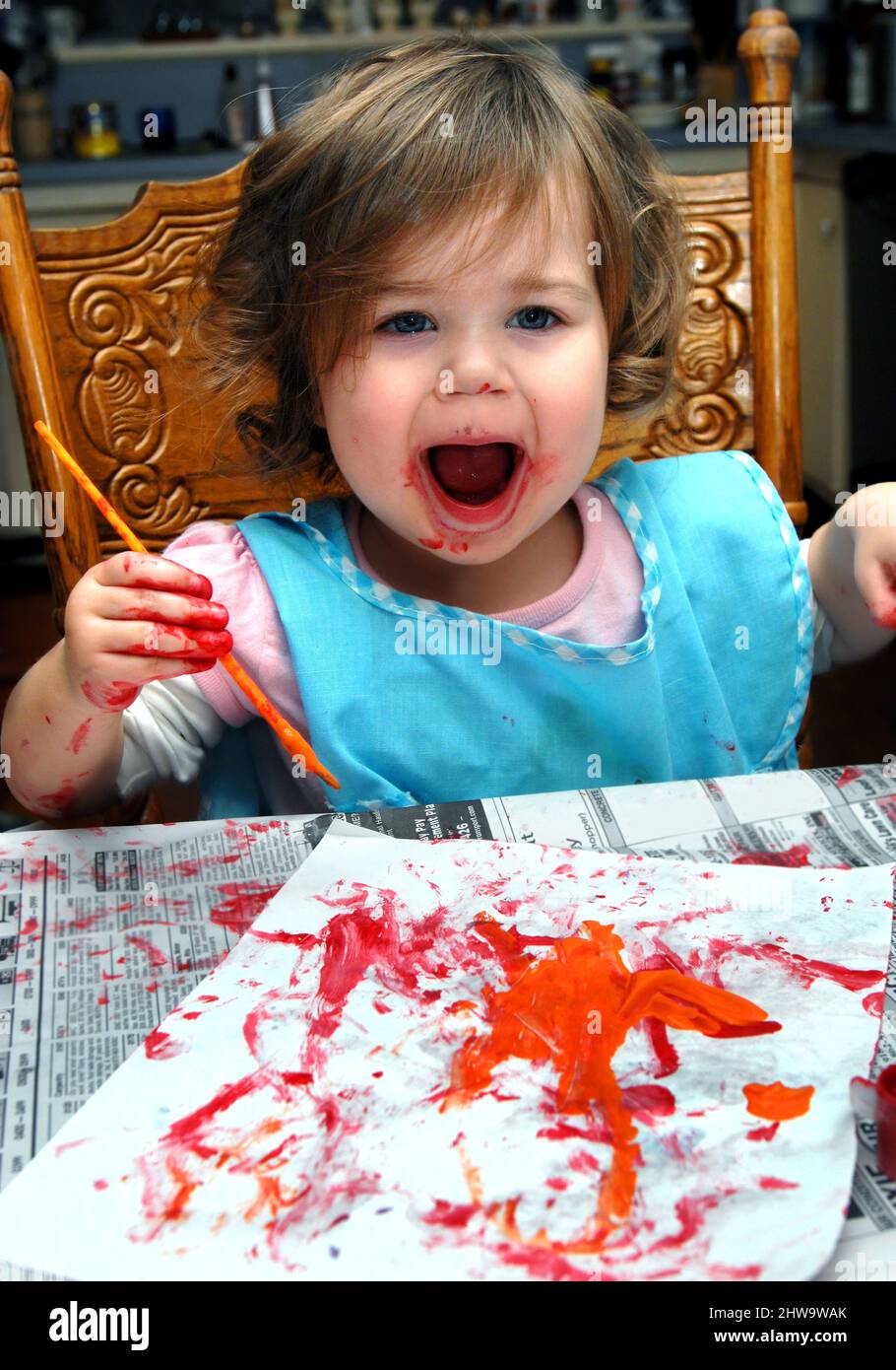 Toddler squaels with joy as she admires her creation. She is painting