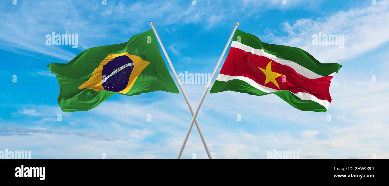 crossed national flags of Brazil and Suriname flag waving in the wind ...