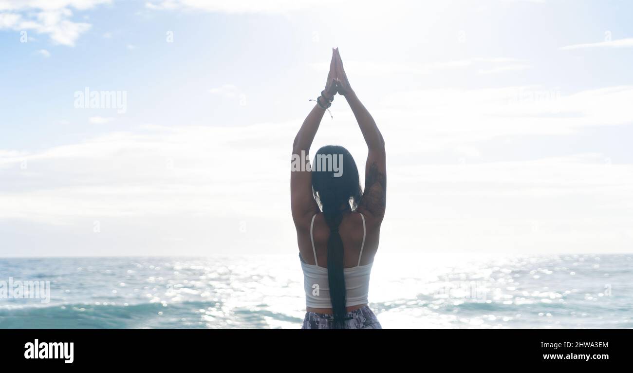 woman in sport clothes practicing yoga and meditating on beach in morning Stock Photo
