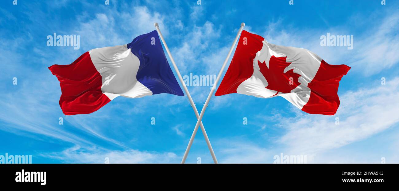 crossed national flags of France and canada flag waving in the wind at ...