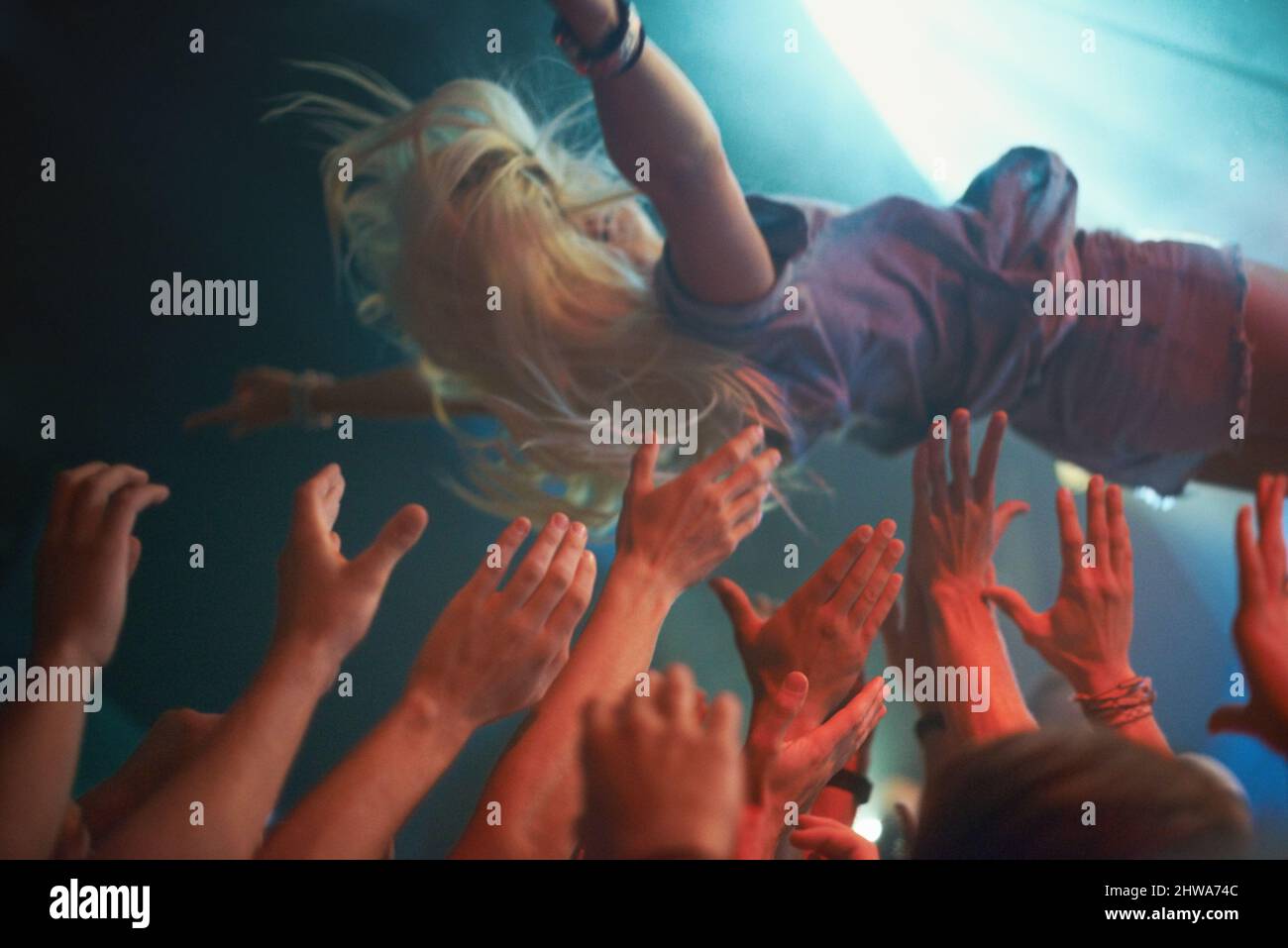 Surfing on a wave of fans. A young woman crowd-surfing at a concert. Stock Photo