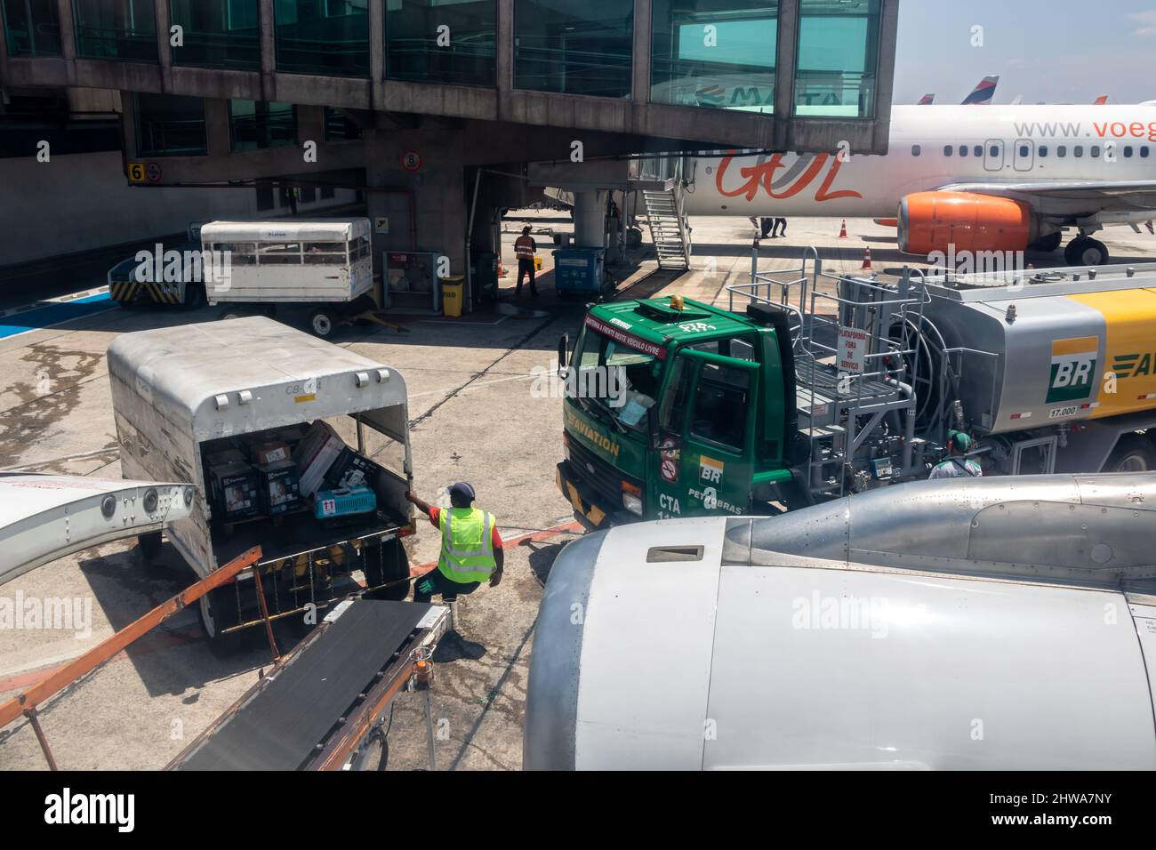 Sao Paulo, Brazil, February 25, 2022. Petrobras Aviation tanker truck with fuel and workers loading luggage in the aircraft yard at Congonhas Airport Stock Photo