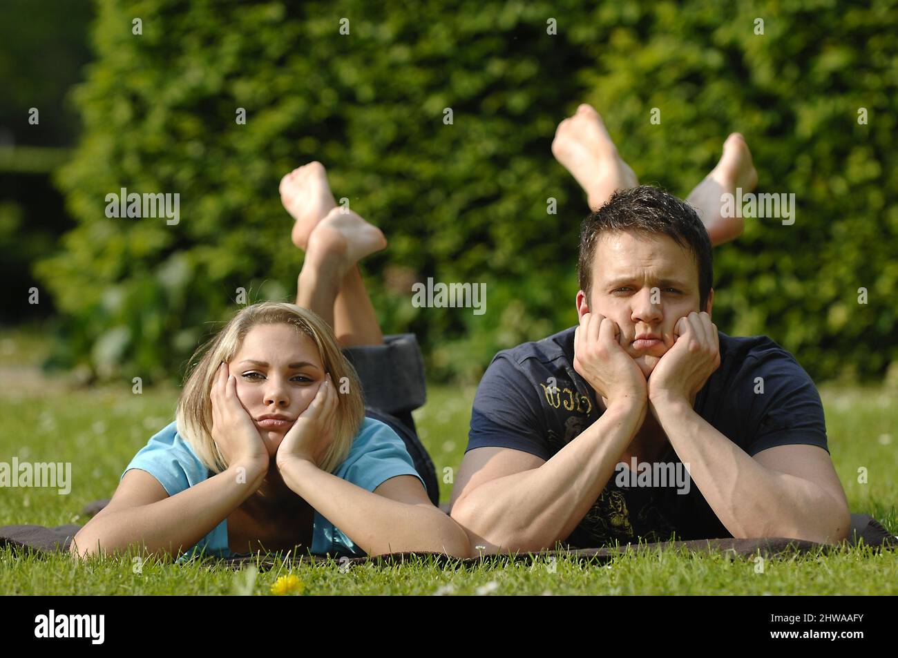 young couple lying bored in a meadow, front view Stock Photo
