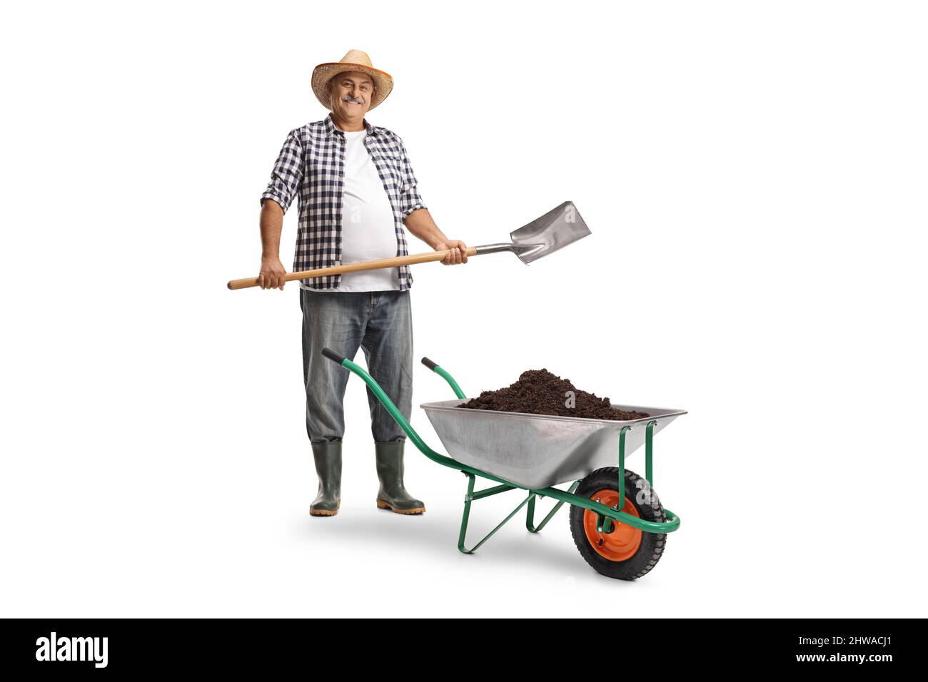 Full length portrait of a mature farmer with a spade and a wheelbarrow ...