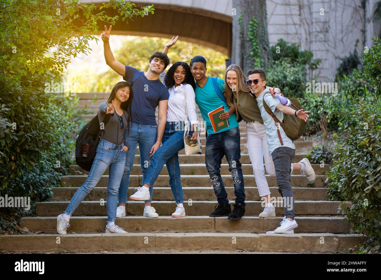 Group of young multiracial students waving at the camera on some stairs Stock Photo