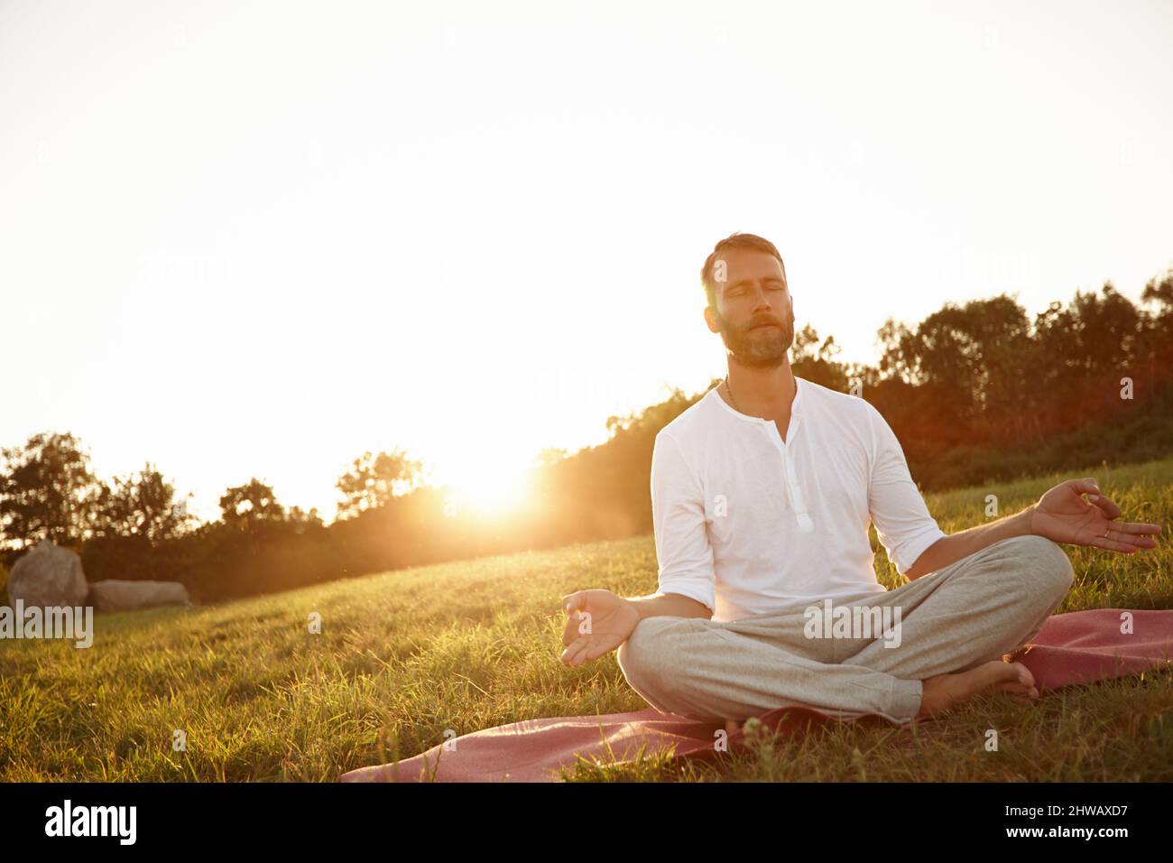 Transcendance at sunset. Shot of a handsome mature man meditating in the outdoors at sunset. Stock Photo