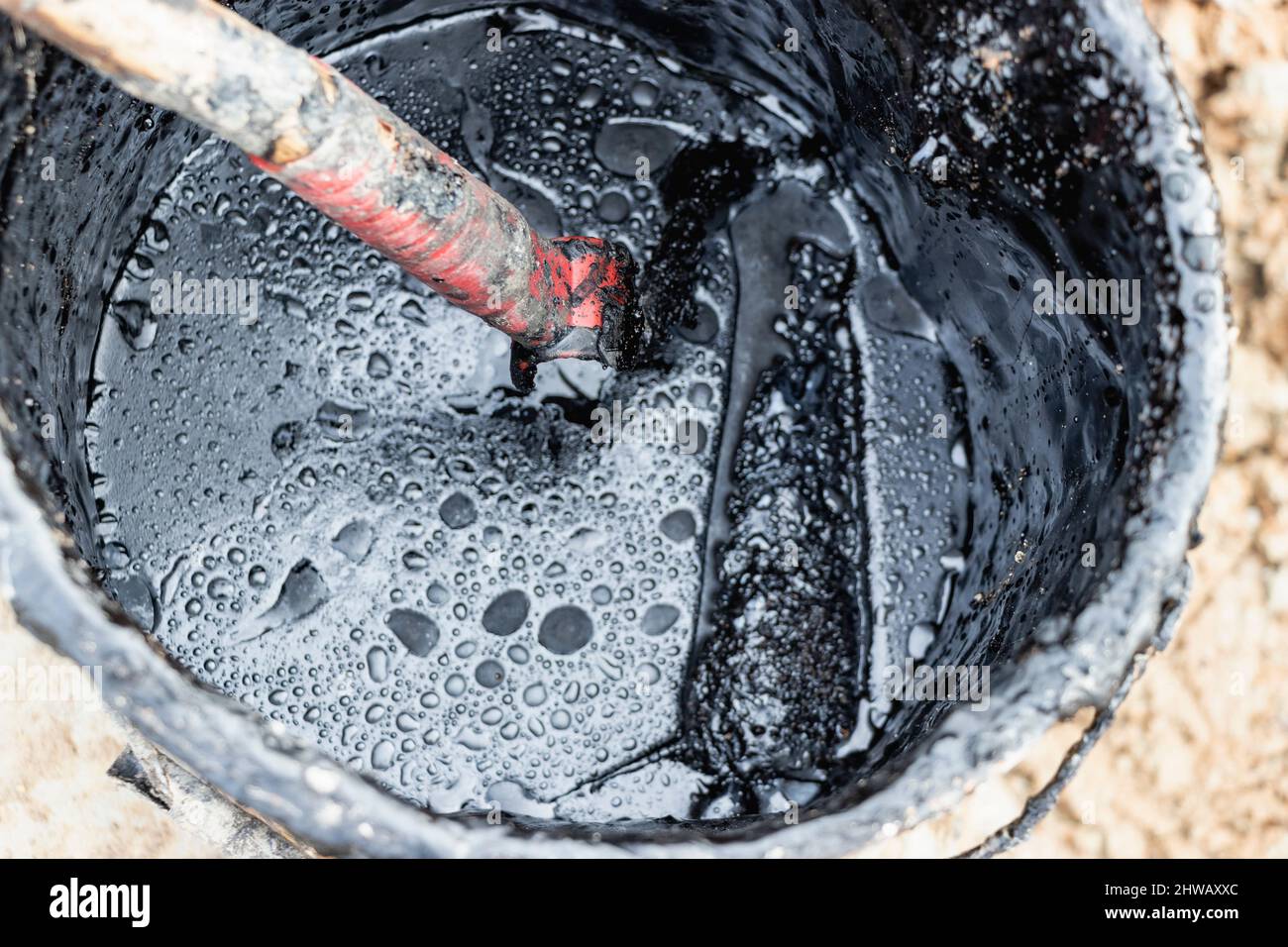 Bituminous mastic for waterproofing in a bucket. Application of bituminous mastic on building structures Stock Photo