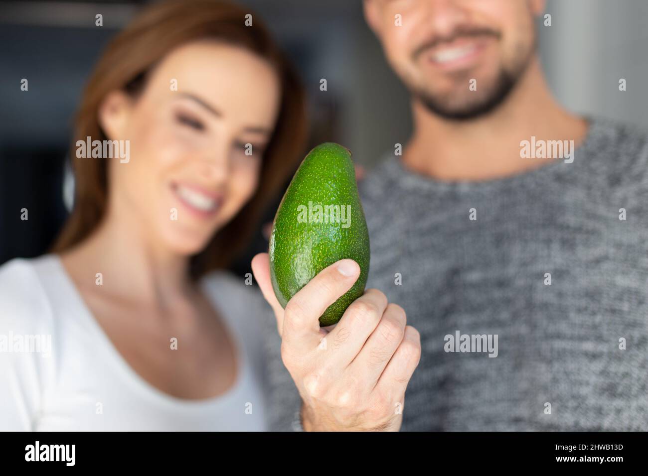 Young caucasian couple with avocado, man holding, depth of field Stock Photo