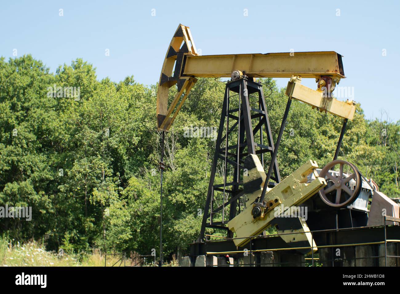 An old oil rig pumping oil out of the ground against a forest of blue skies. Extraction of black