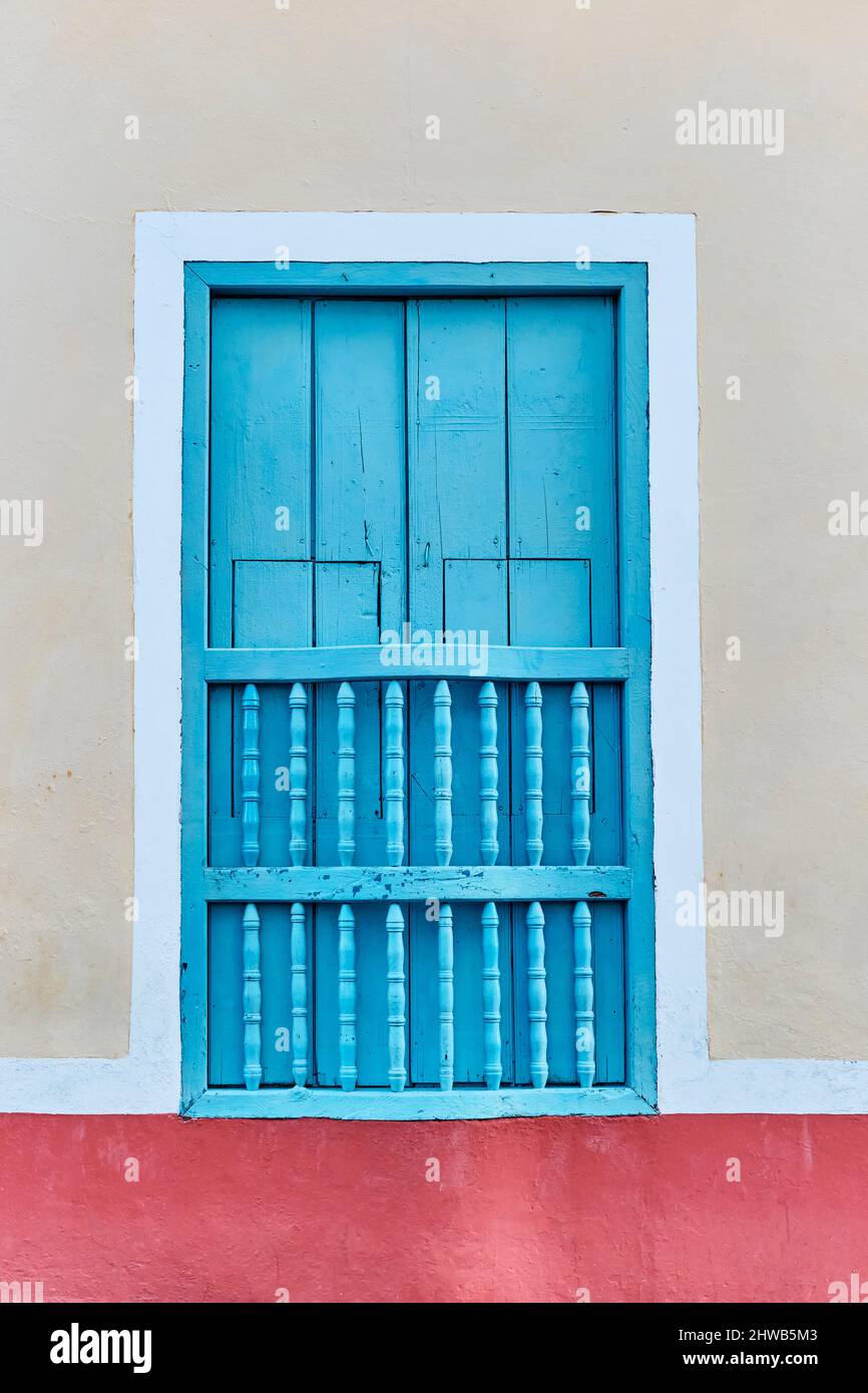 Typical window with blue wooden shutters and bars in the old colonial
