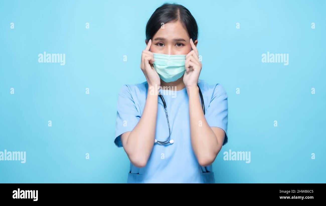 Asian Thai nurse or doctor wearing mask feeling worry isolated in studio on blue background Stock Photo