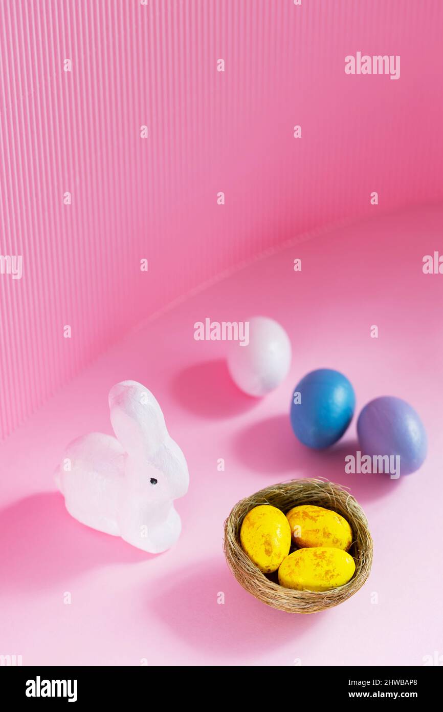 Easter eggs and rabbit on a pink background. Multicolored eggs for Easter celebration. Copy space Stock Photo