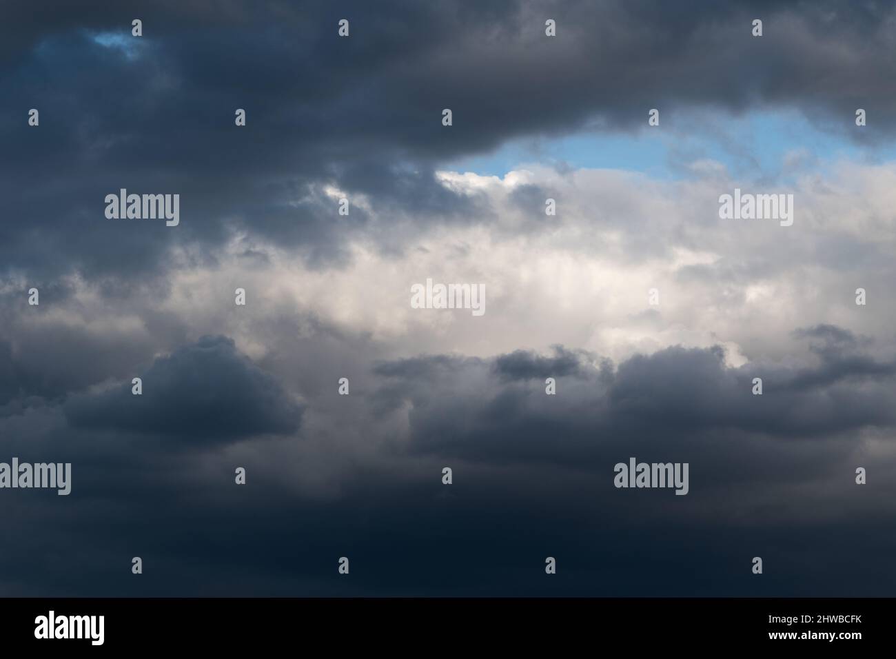 White cumulus cloud framed with dark ominous clouds - cloudscape Stock Photo