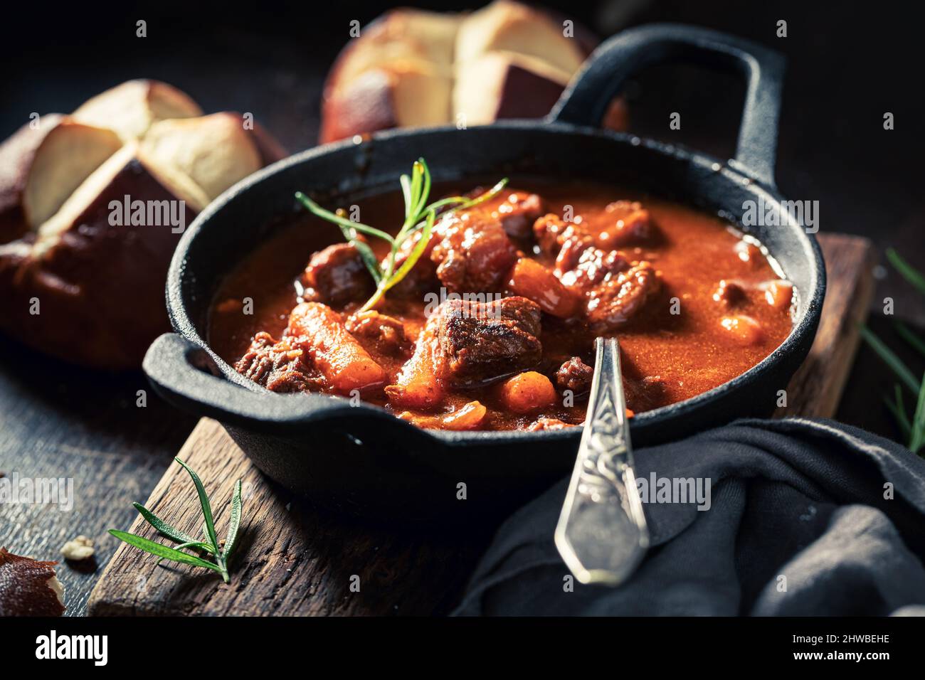 Hot and tasty goulash served with fresh hot buns on dark plate Stock Photo
