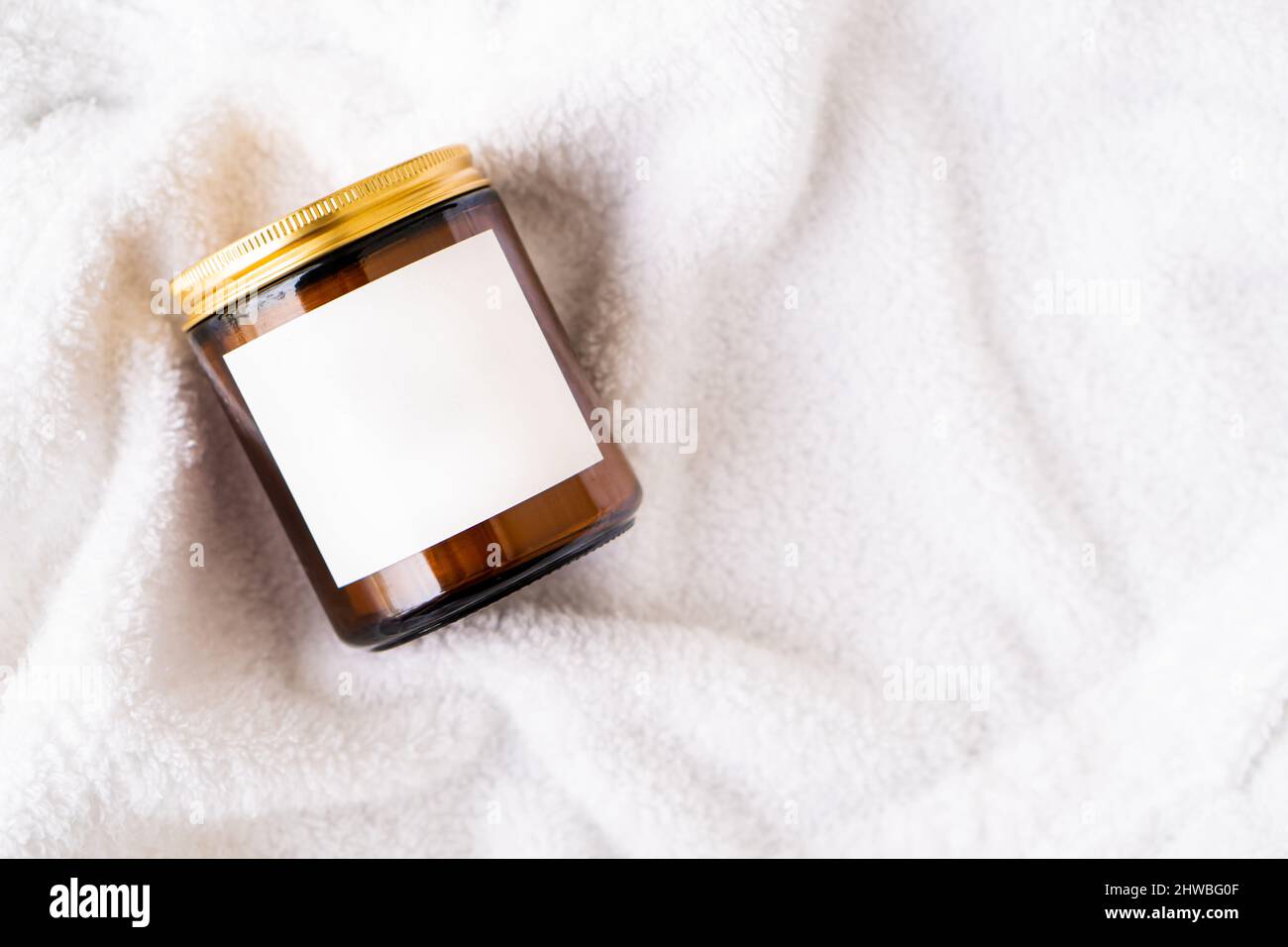 Amber glass jar with metal lid and blank label on white cotton fabric ...