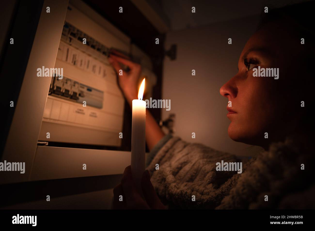 Woman checking fuse box at home during power outage or blackout. No electricity concept Stock Photo