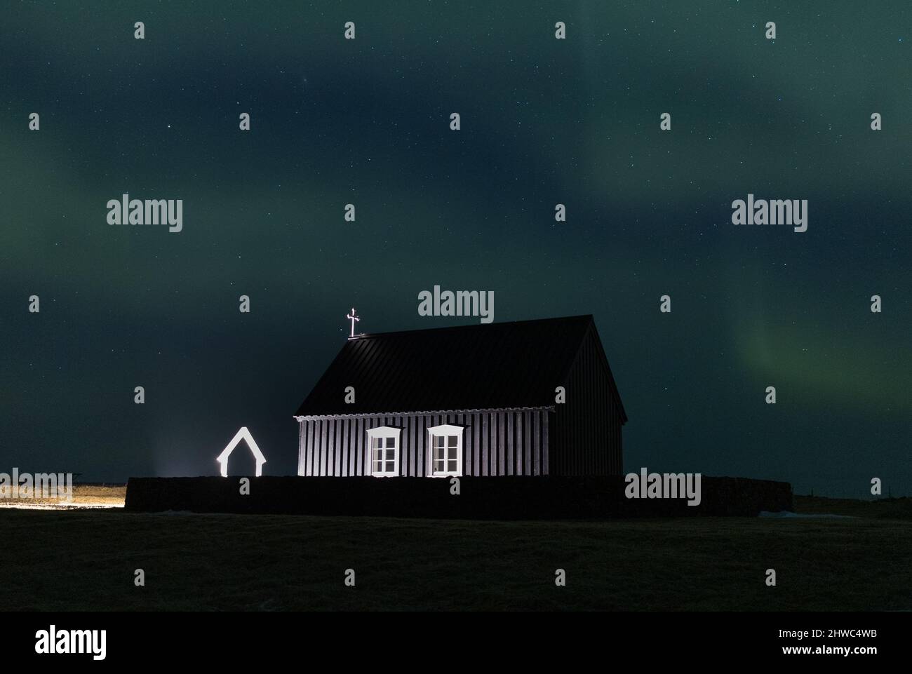Northern lights over a black church in Iceland Stock Photo