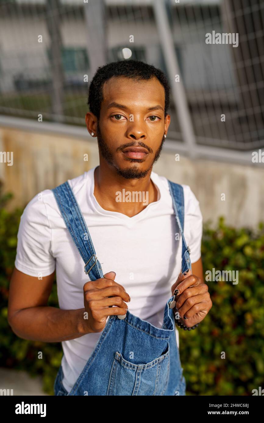 Guy posing in a white shirt and overalls Stock Photo Alamy