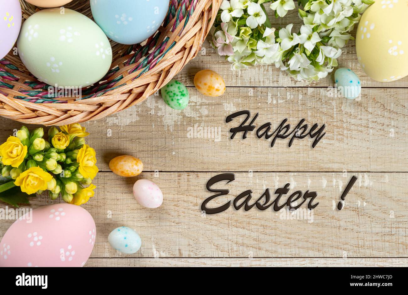 Easter border of colored easter eggs and flowers on a rustic wooden
