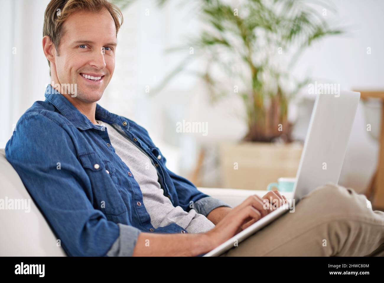 Lazy day with my laptop. Portrait of a handsome man using his laptop at home. Stock Photo