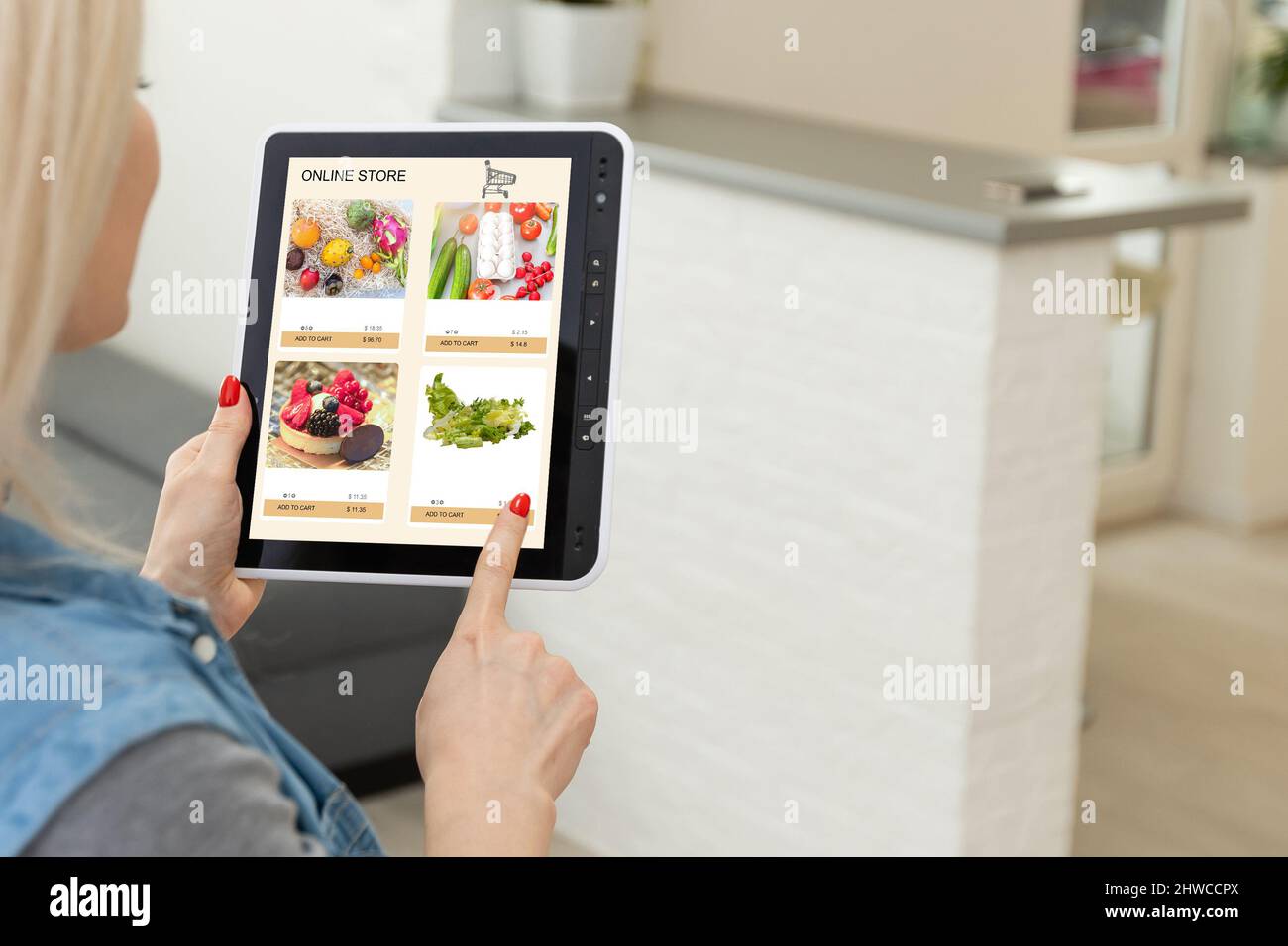 Woman shopping food online using a digital tablet at the kitchen, closeup view on a tablet