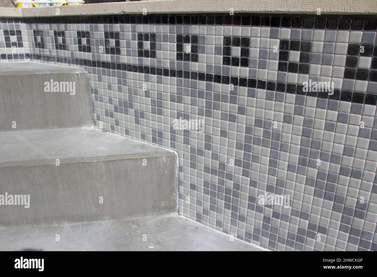 Tiles being applied to refurbish a swimming pool Stock Photo