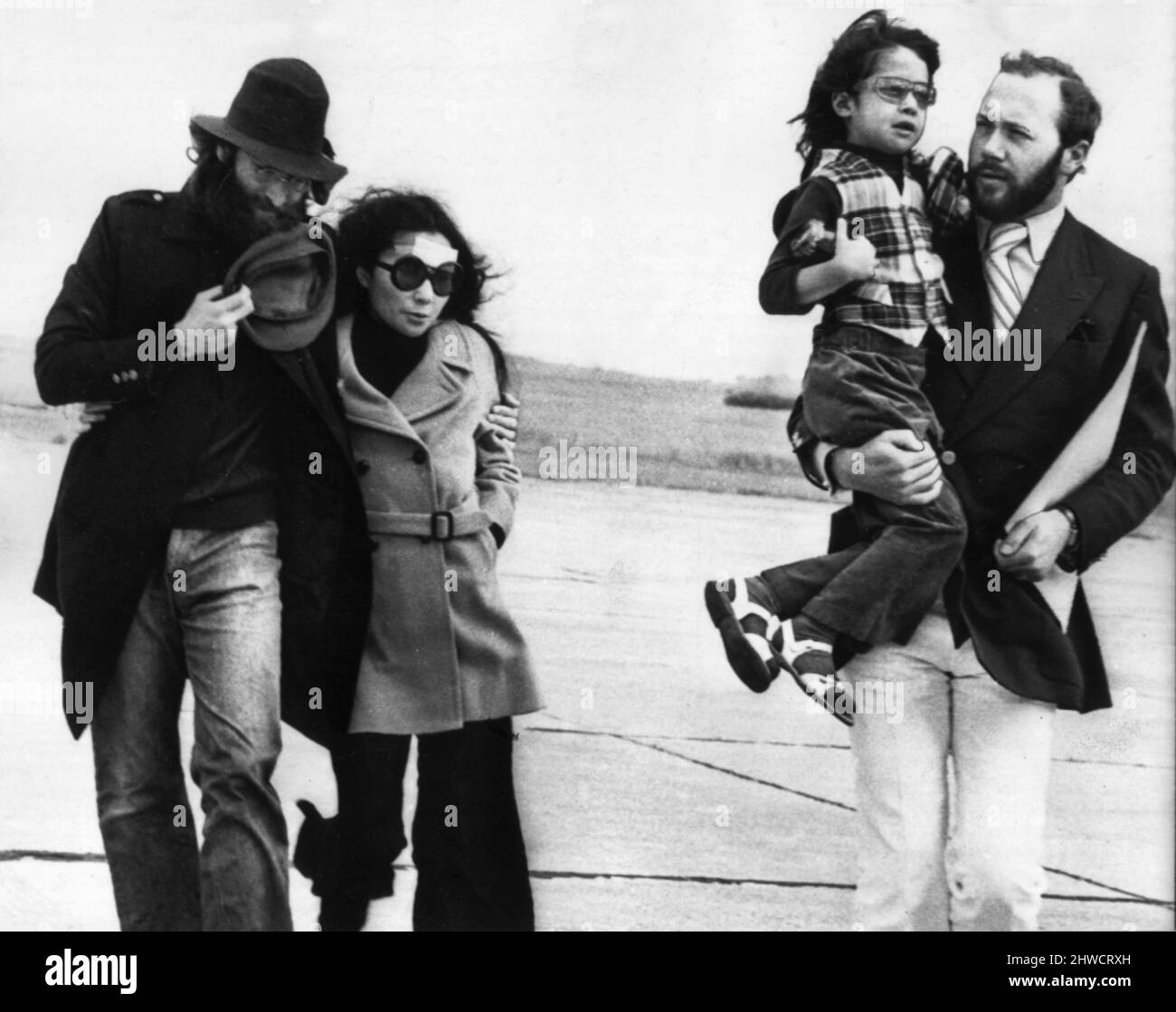 John Lennon and Yoko Ono at Dalcross Airport in Inverness to board a private jet to London.Lennon's beard has been partly shaved away to allow a nasty gash to be stitched hence he is holding her hat at his chin and Yoko has a plaster on her forehead after a car crash in Durness in 1969. Kyoko is being carried by Peter Brown. Stock Photo