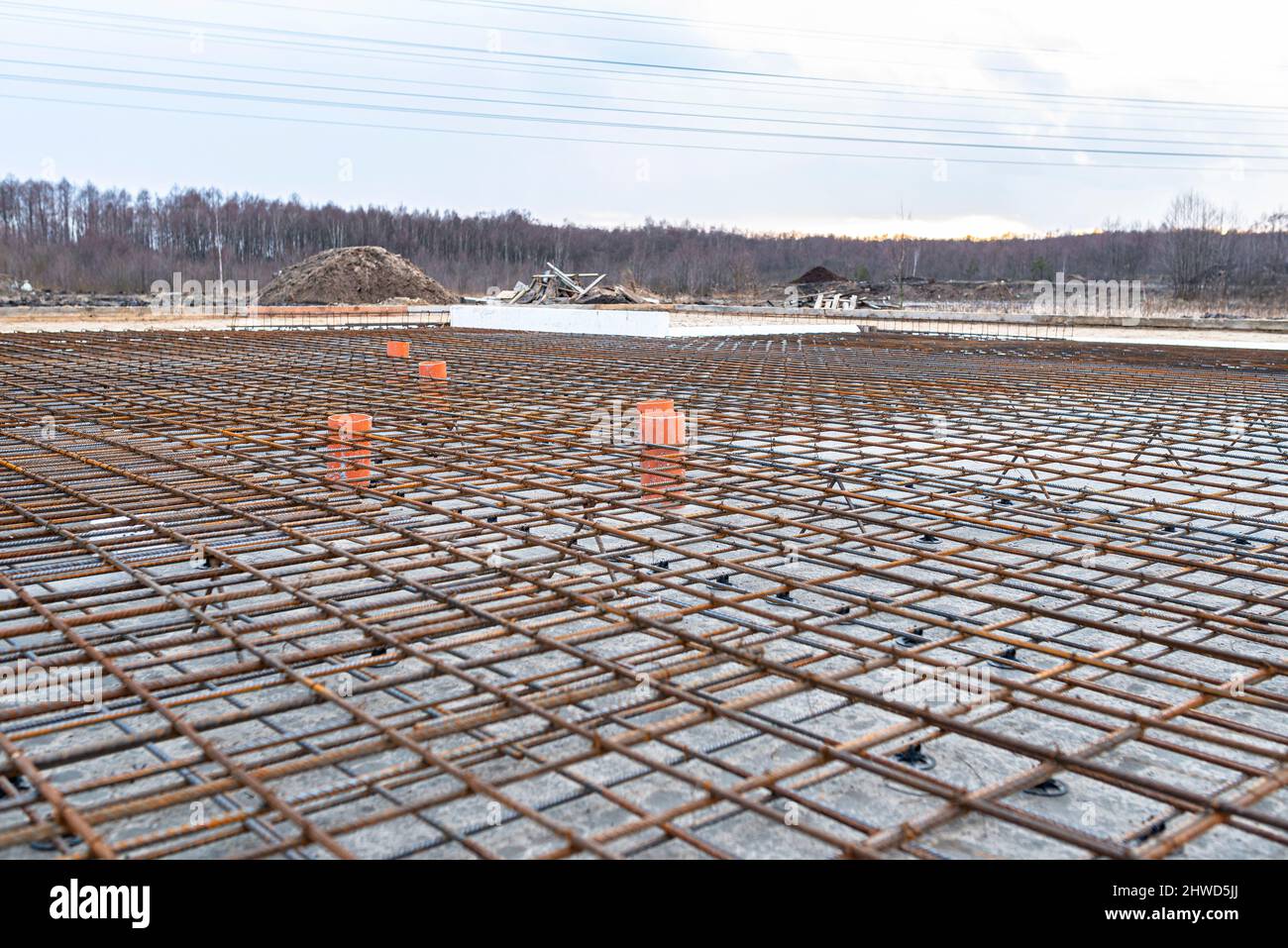 The foundation slab is made of reinforcement rods, bound with tie wire, visible sewage pipes