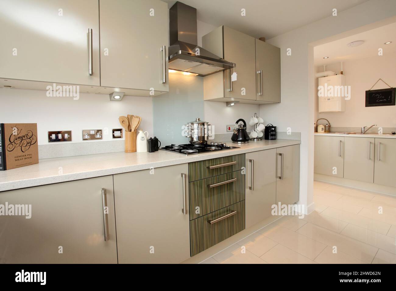 Kitchen in modern showhome, fitted kitchen units, floor and wall cupboards, through to laundry utility room Stock Photo
