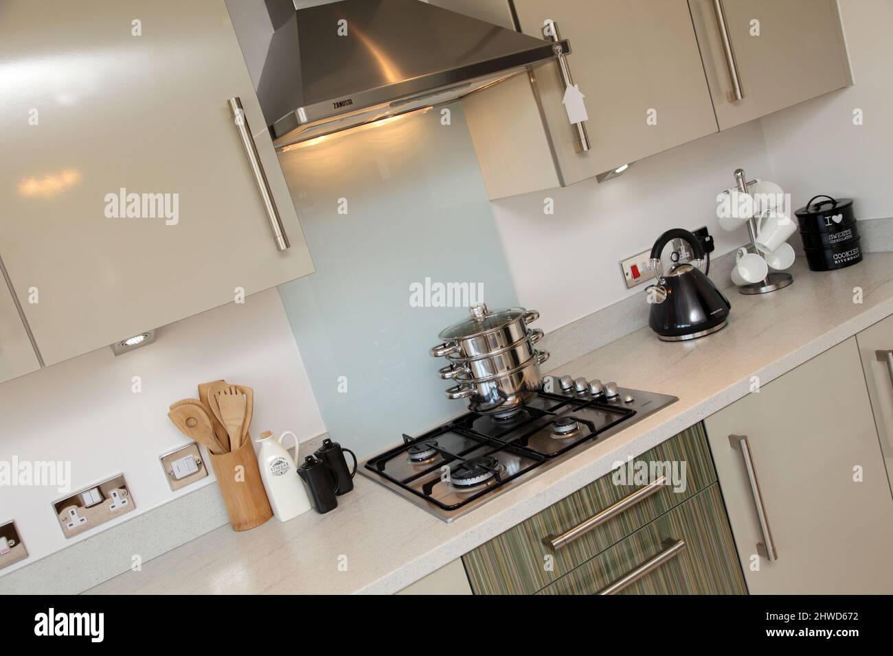 Pans stacked on gas cooker hob in kitchen of modern showhome, fitted kitchen units, floor and wall cupboards Stock Photo