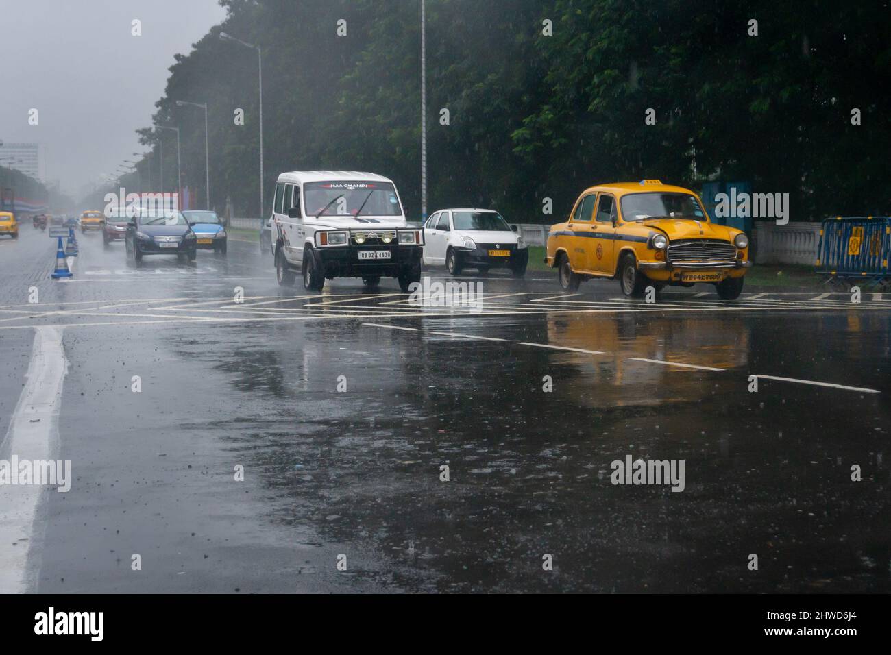 Kolkata, West Bengal, India - 17th August 2019 : Image shot through raindrops falling on wet glass, cars waiting in traffic signal - monsoon stock ima Stock Photo