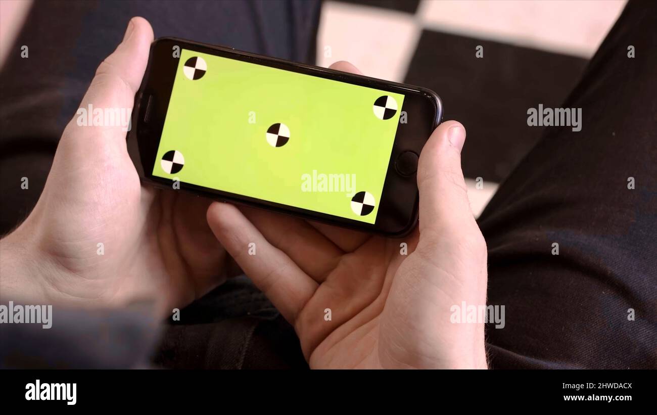 Closeup of man holding phone with green screen. Stock footage. Man