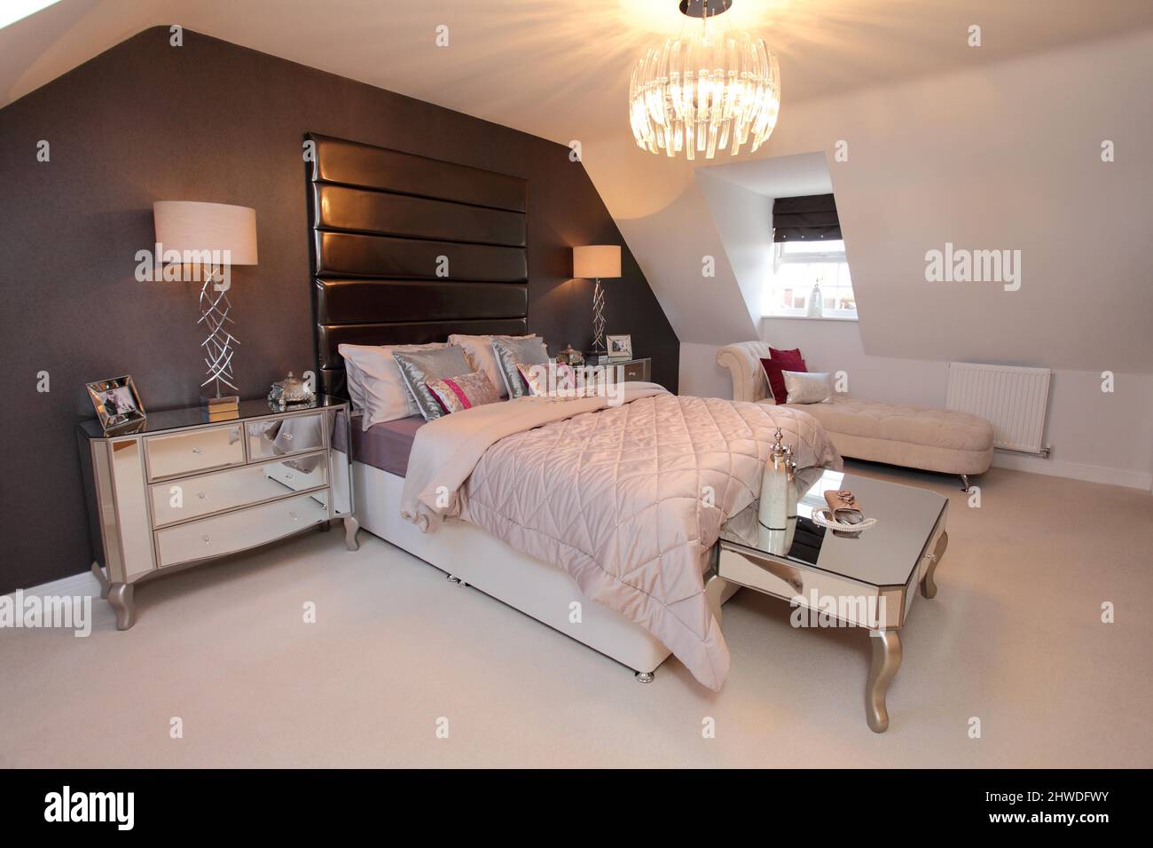 Bedroom in top floor loft conversion, slanted roof,dormer windows,padded headboard,quilted bedspread, Stock Photo